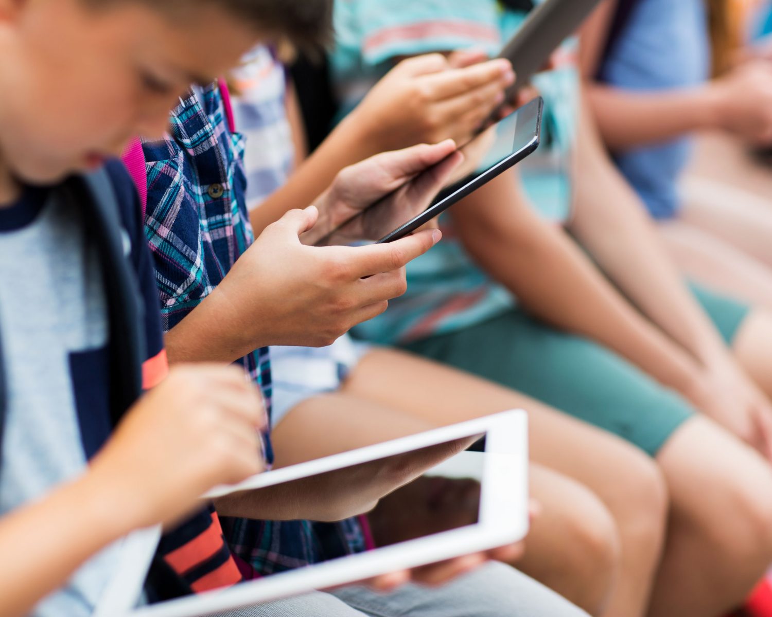 primary education, childhood, technology and people concept - close up of elementary school students with backpacks and tablet pc computers
