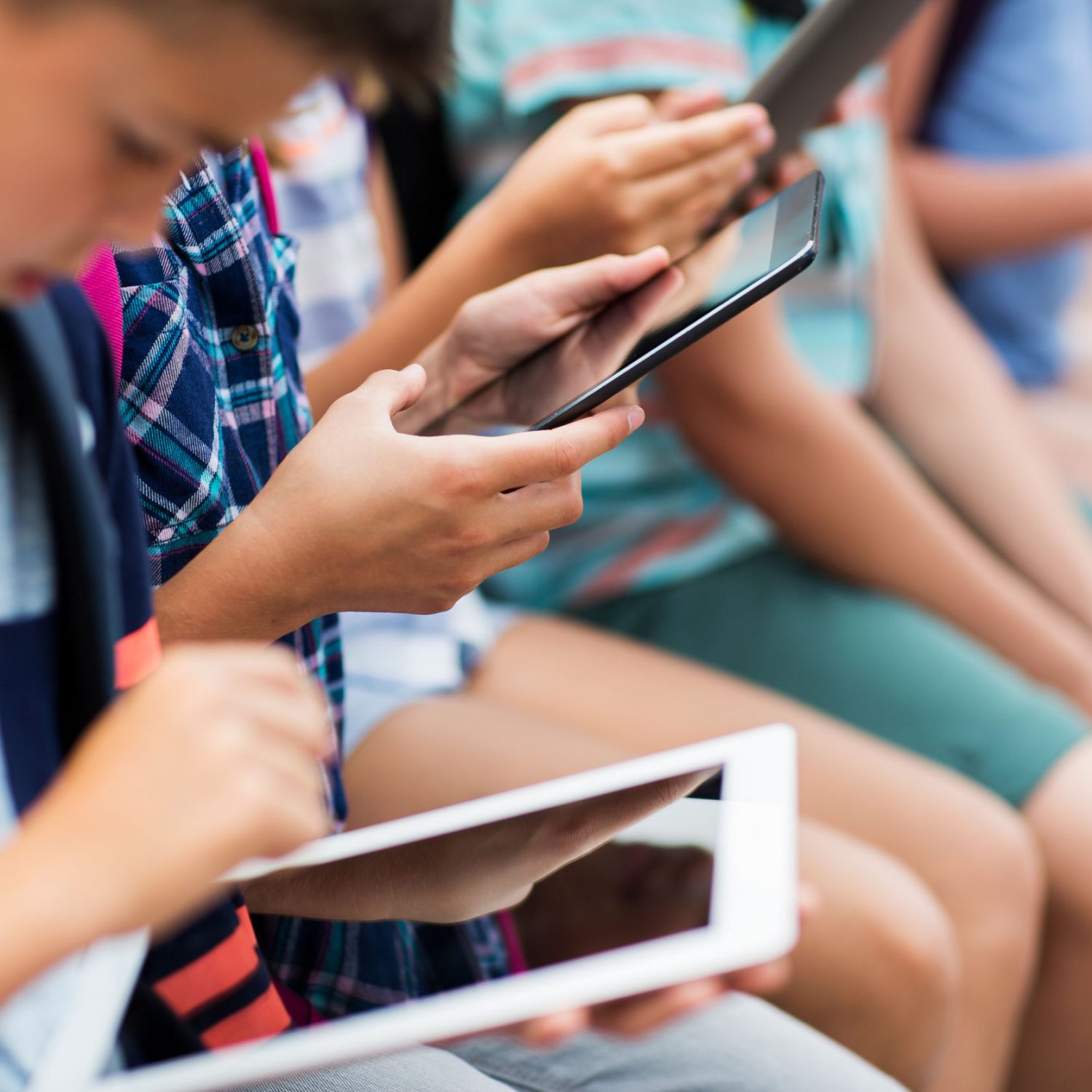 primary education, childhood, technology and people concept - close up of elementary school students with backpacks and tablet pc computers